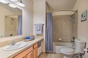 A bathroom with a sink, mirror, towel rack, shower curtain, bathtub, and toilet. - Idyllic Fairplay Cabin w/ Mt Silverheels View (Fairplay)