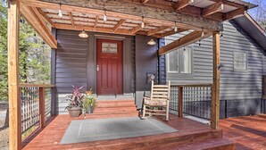 A wooden deck with a red door, a wooden chair, and a potted plant. - 'house in the Woods' in Ooltewah w/ Fire Pit! (Ooltewah)