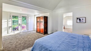 Une chambre avec un grand lit, une armoire en bois et une porte-fenêtre coulissante donnant sur un balcon.