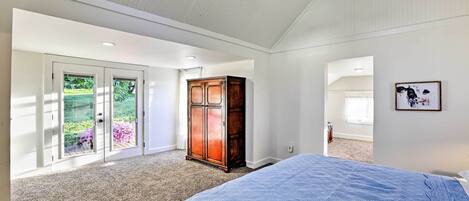 Een slaapkamer met een groot bed, een houten kast en een schuifdeur naar een balkon.