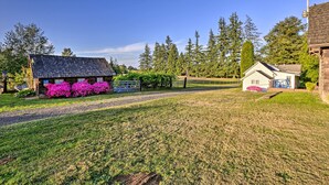 Une propriété rurale comprenant une maison, un petit bâtiment et un espace clos agrémenté de plantes à fleurs.