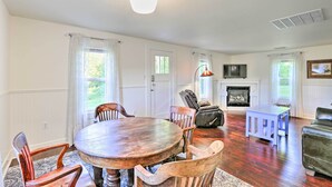 Un coin repas avec une table ronde en bois et des chaises, une cheminée, et un salon avec un canapé et un téléviseur.