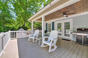 A covered deck with white rocking chairs and a grill area. - Lake Norman Retreat w/ Dock ~ 1 Mi to Marina! (Mooresville)