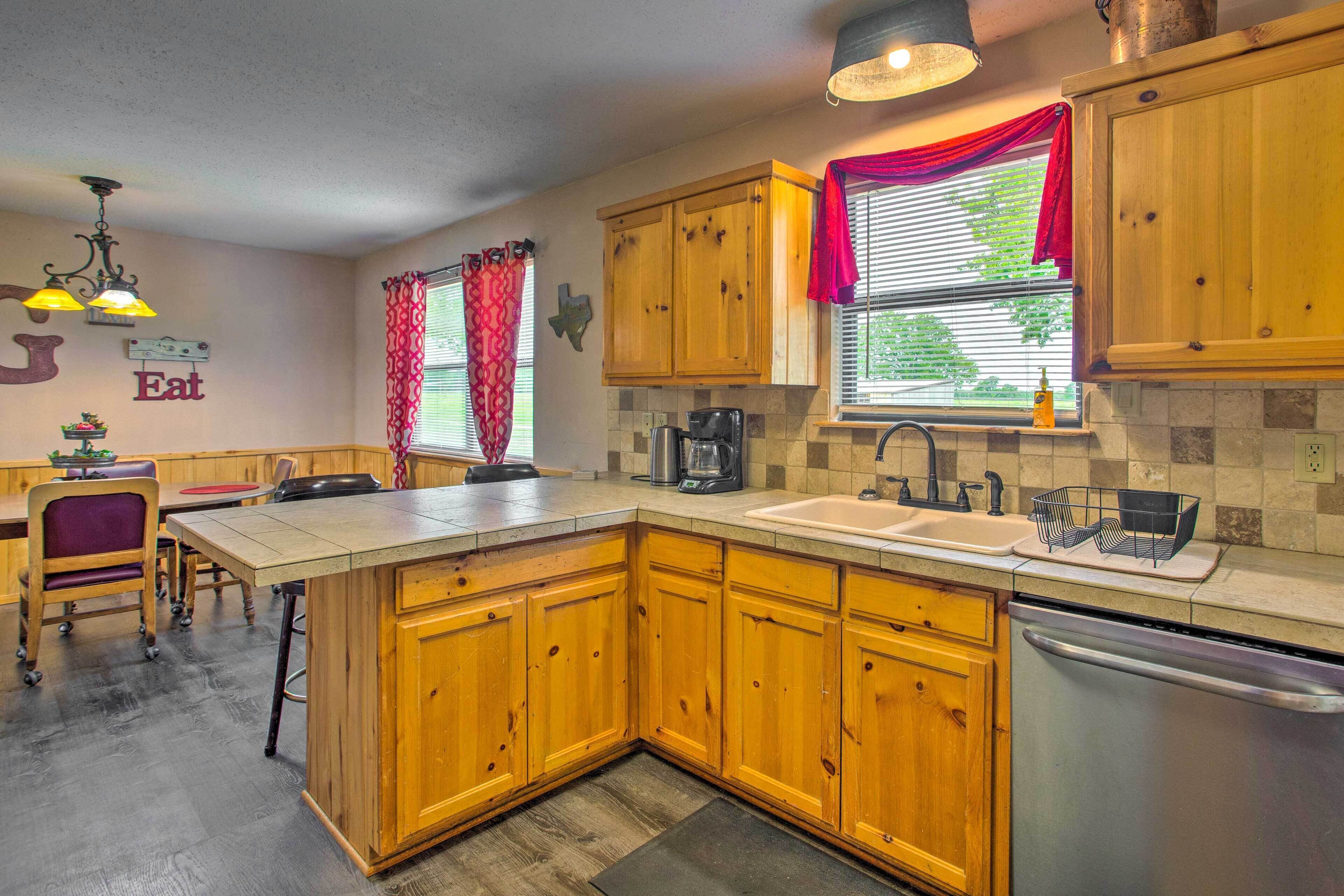 A kitchen with wooden cabinets, a central island, a sink, and a dishwasher.