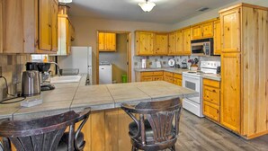 A kitchen with wooden cabinets, a central island with bar stools, a microwave, stove, and a refrigerator. - Emory Escape w/ Pond Access < 13 Mi to Lake! (Emory)
