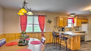 A kitchen with wooden cabinets, a central island, and a dining area with a table and chairs. - Emory Escape w/ Pond Access < 13 Mi to Lake! (Emory)