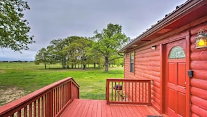 A wooden cabin with a red deck, a barbecue grill, and a welcome mat. - Emory Escape w/ Pond Access < 13 Mi to Lake! (Emory)