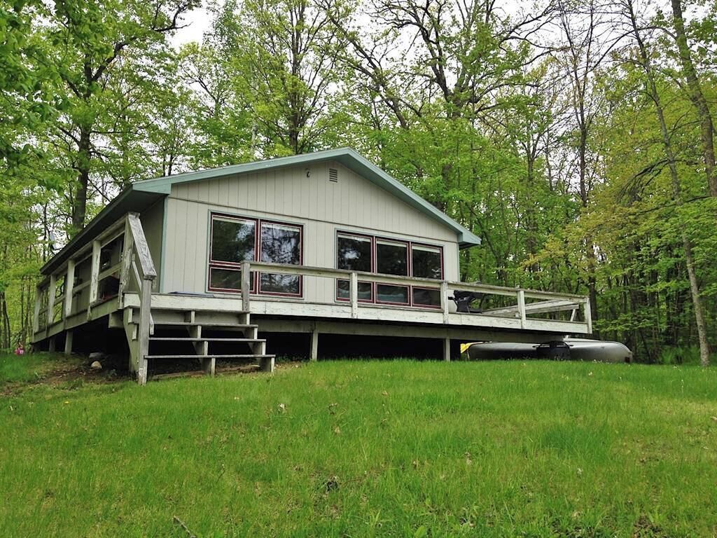 A two-story house with a balcony, surrounded by trees.