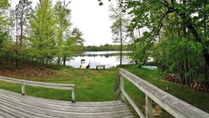Une terrasse en bois qui mène à un lac, avec des bancs et un quai.