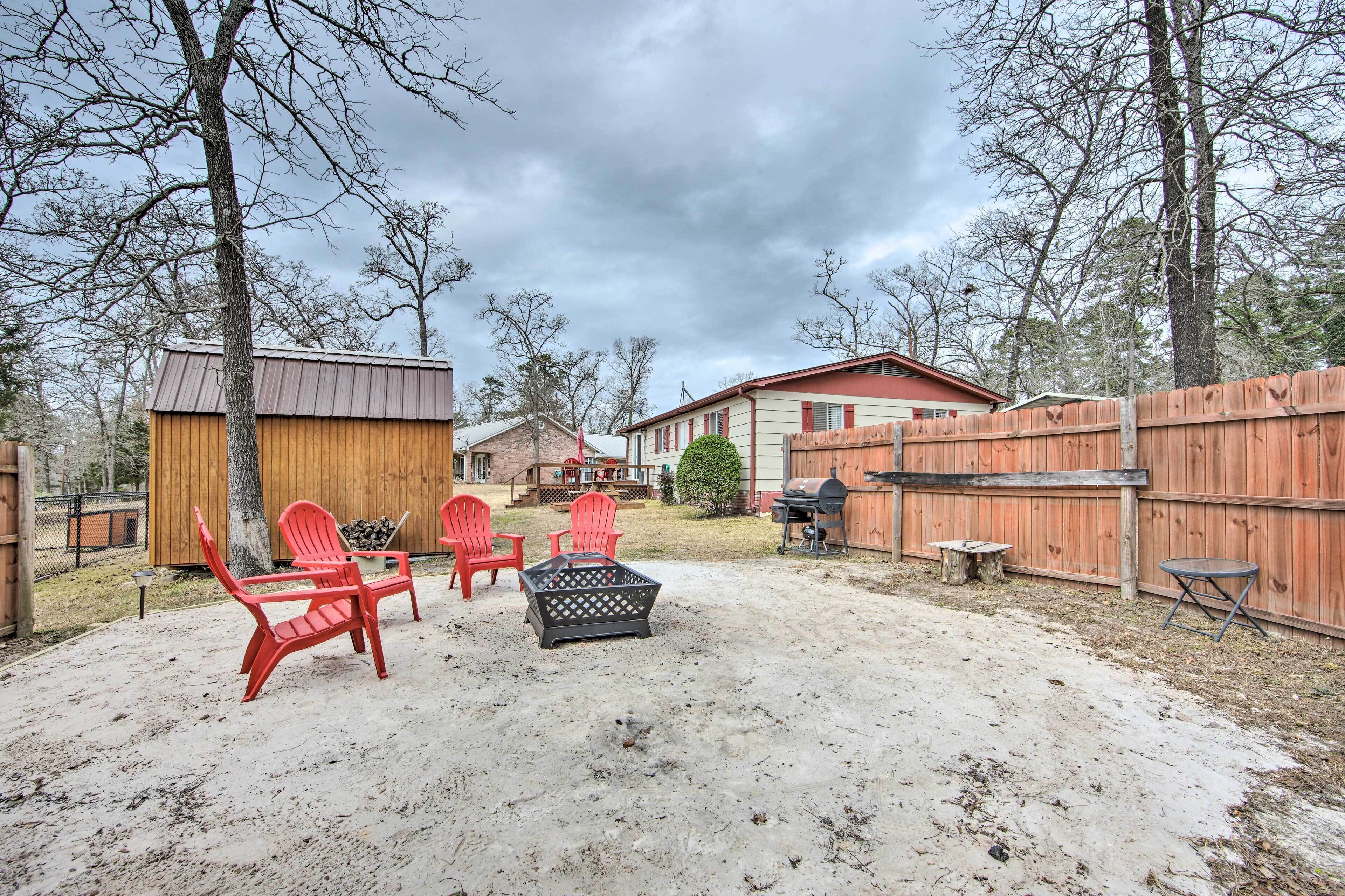 A backyard with a wooden deck, red chairs, a barbecue grill, and a shed.