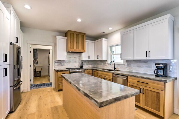 A modern kitchen with white cabinets, a granite countertop, and a wooden ceiling.