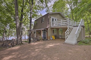 A cabin with a deck and stairs, surrounded by trees and a lake. - Lakefront New Auburn Apt w/ Sauna & Sun Porch (New Auburn)