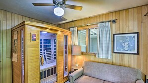 Una habitación con paneles de madera que incluye una sauna, un sofá, una lámpara y un cuadro en la pared.