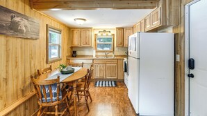 A wooden interior with a kitchen area, including a dining table, chairs, and a refrigerator. - Cozy Island Park Getaway By ATV Trails & Reservoir (Island Park)