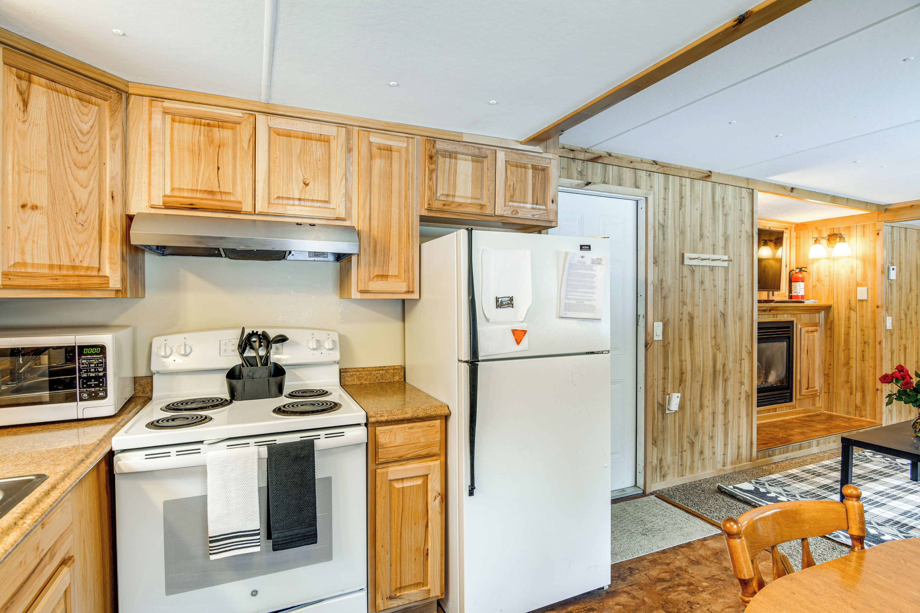 Une cuisine avec des meubles de rangement en bois, un fourneau blanc, un réfrigérateur et un four à micro-ondes.
