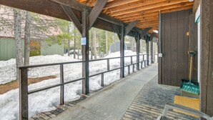 A covered wooden deck with a metal railing, a wooden door, and a broom leaning against the wall. - Cozy Island Park Getaway By ATV Trails & Reservoir (Island Park)