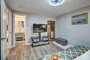 A bedroom with a bed, a TV, a storage unit, and a door leading to a bathroom.