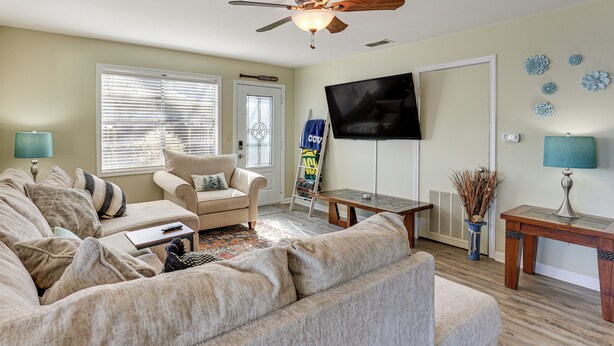 A living room with a ceiling fan, a TV, and a large window with blinds. - Classic Lake O' the Pines Retreat! Dock, Fire Pit (Jefferson)