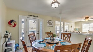 A dining area with a wooden table, blue placemats, and wooden chairs. There is a white cart with a blue basket and a white cabinet with drawers. - Classic Lake O' the Pines Retreat! Dock, Fire Pit (Jefferson)