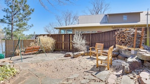 A backyard with a wooden swing set, a stone patio, and a wooden deck. - Classic Lake O' the Pines Retreat! Dock, Fire Pit (Jefferson)