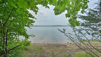 A natural landscape with a body of water, trees, and a grassy area.