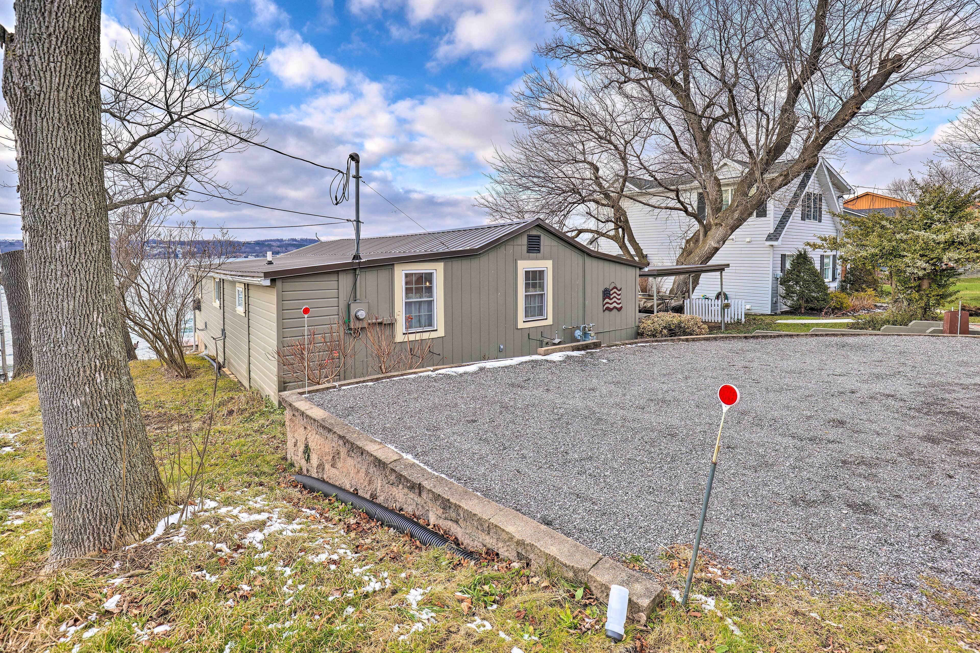 A residential property with a gravel driveway, a small shed, and a house with a sloped roof.