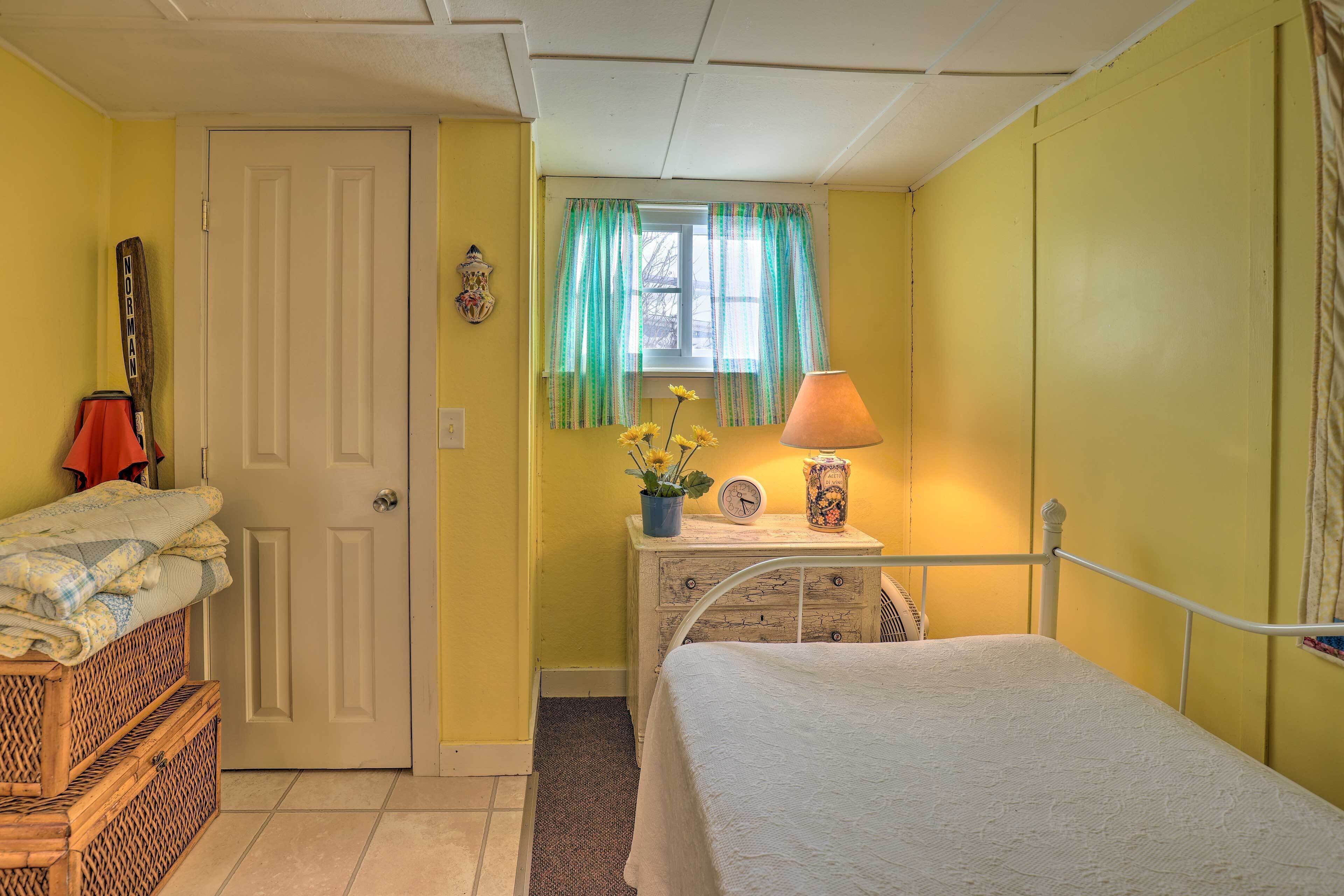 A bedroom with a bed, a dresser, a lamp, and a window with curtains.