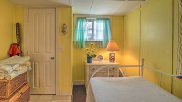 A bedroom with a bed, a dresser, a lamp, and a window with curtains.