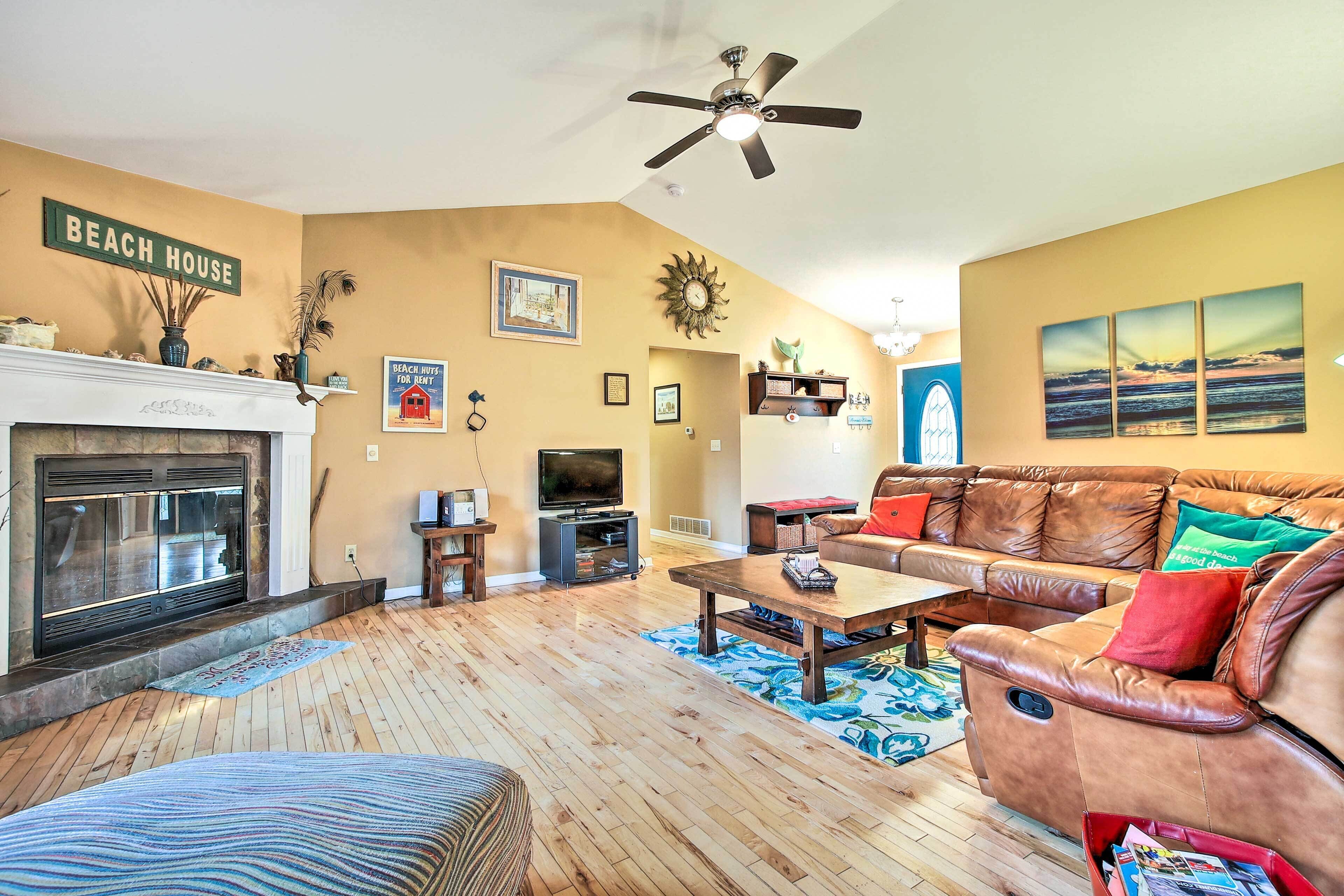 A living room with a fireplace, leather sofa, and a ceiling fan.