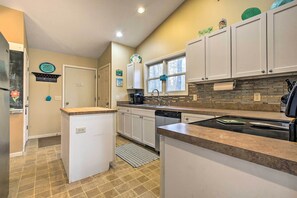 A modern kitchen with white cabinets, a built-in dishwasher, and a countertop with a kettle. - Lake Michigan Gem < Half-mi to Private Beach! (Mears)