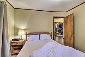 Ein Hotelzimmer mit einem hölzernen Bett, einem Nachttisch mit Lampe und einer Tür zu einem Flur.