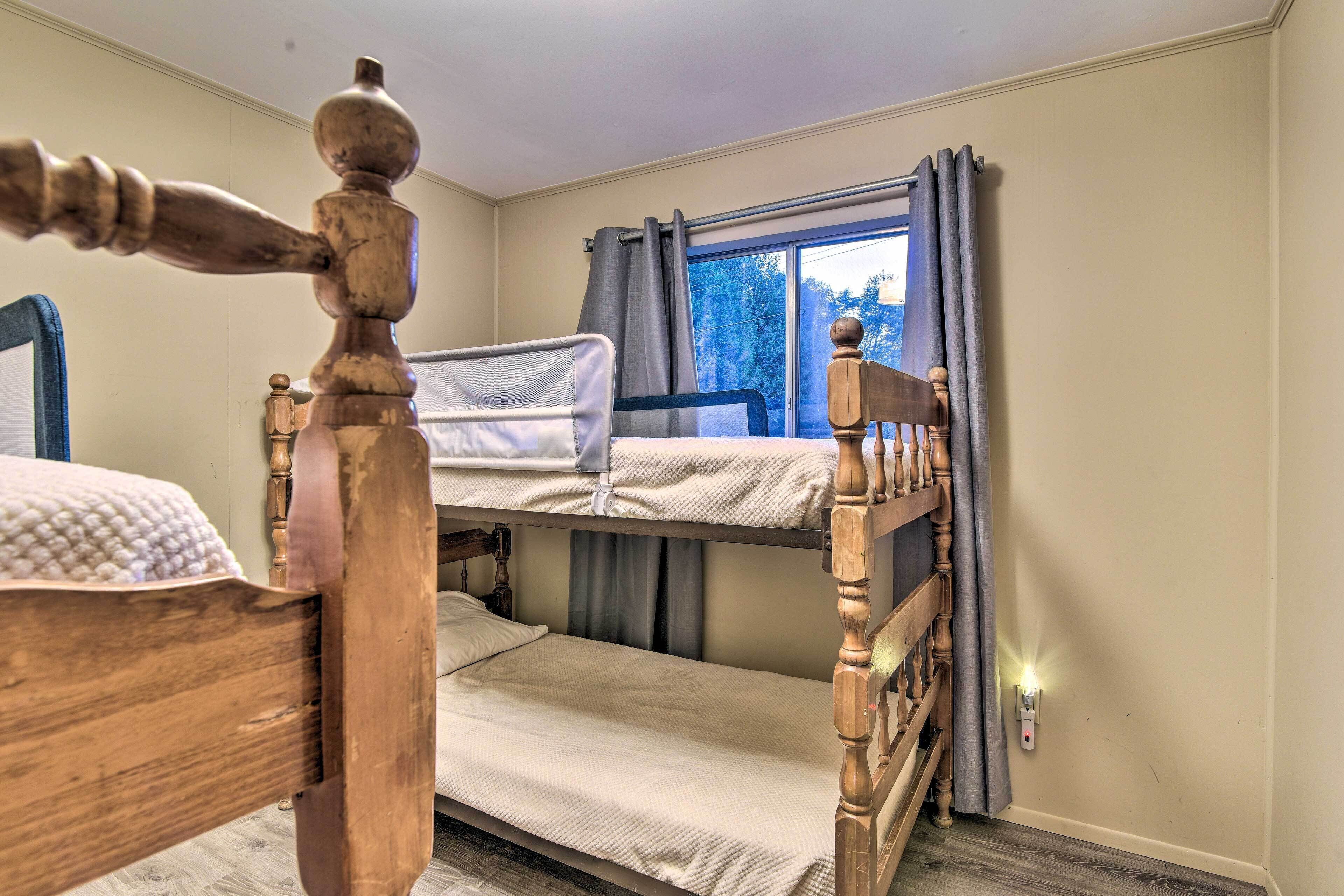 Een slaapkamer met stapelbed, een houten hoofdeinde, een raam met gordijnen en een nachtlampje.