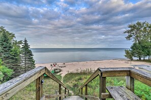 A wooden staircase leading to a beach with a view of the sea and trees.