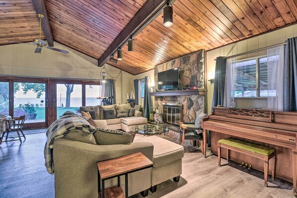 A spacious living room with a wooden ceiling, a large TV, a piano, and a cozy seating area.