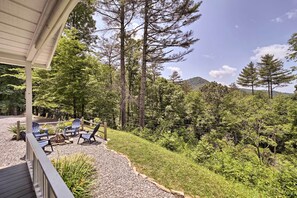 En overdækket terrasse med udendørs siddepladser og udsigt til et skovområde.