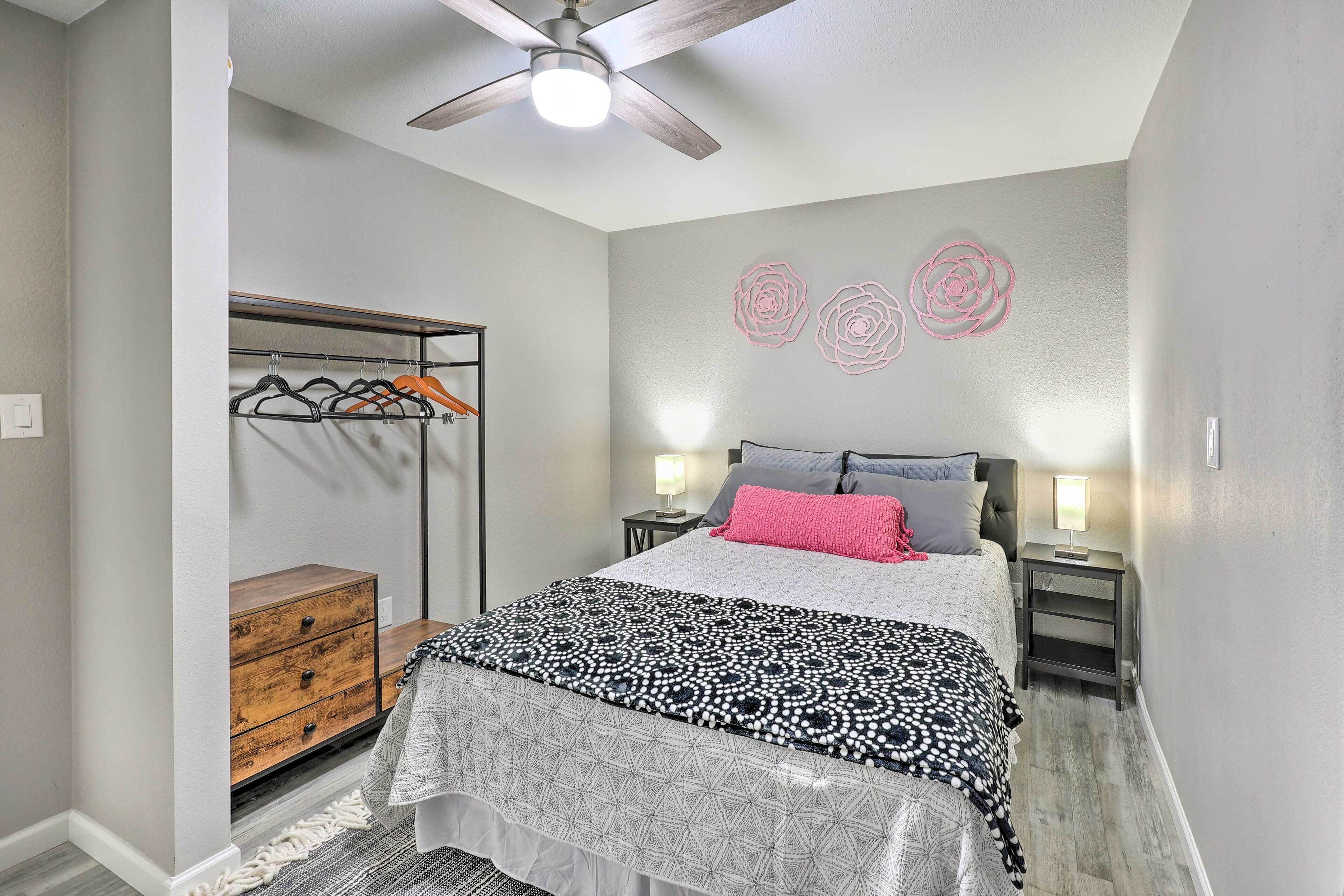 A bedroom with a bed, a wardrobe, a nightstand, and a ceiling fan.