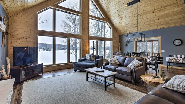 A spacious living room with large windows, a fireplace, and a cozy seating area. - Lakefront Cottage in Iron River: 3 Mi to Skiing! (Iron River)