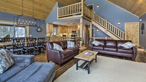 A spacious living area with a high ceiling, wooden flooring, and a central seating arrangement. - Lakefront Cottage in Iron River: 3 Mi to Skiing! (Iron River)