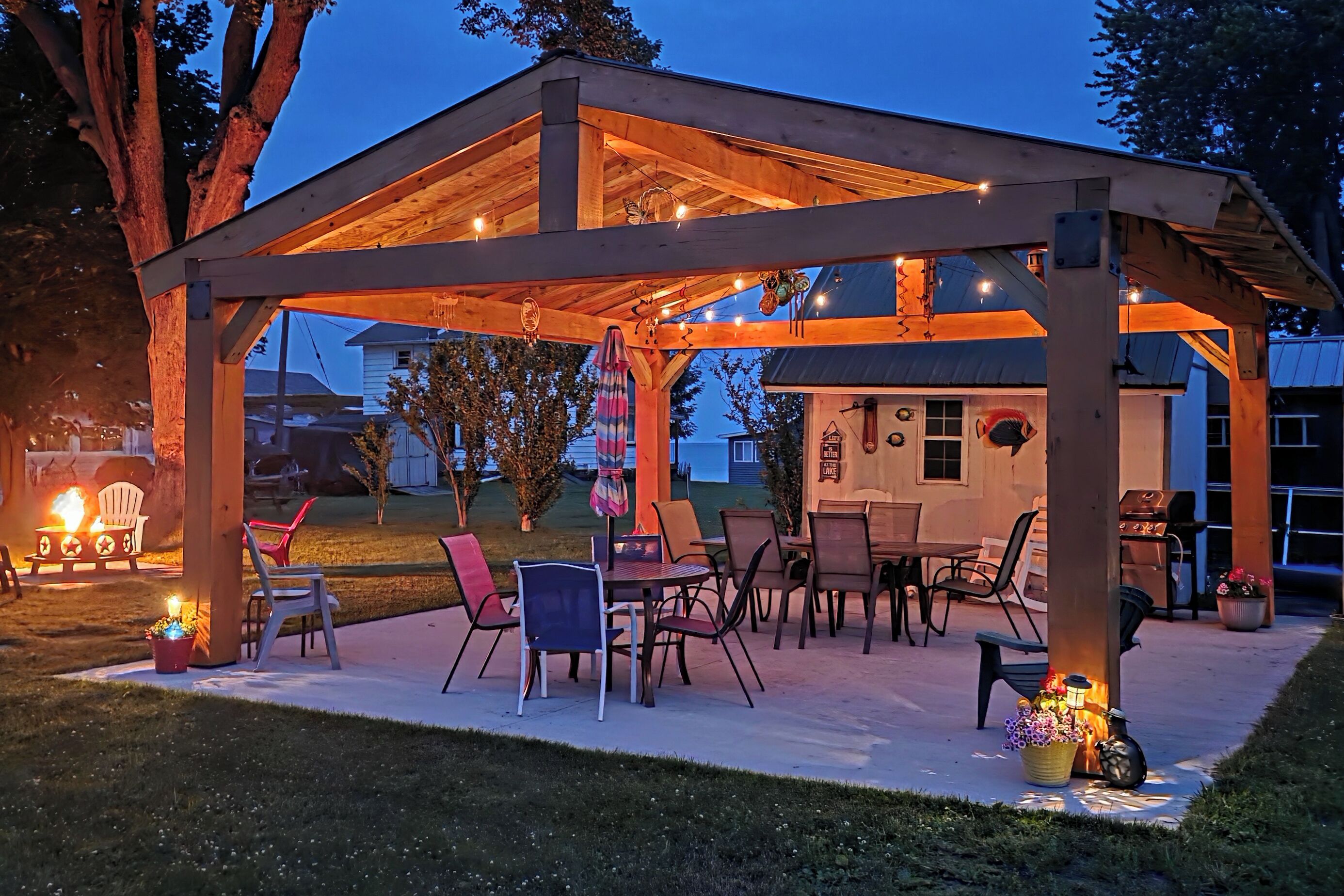 Un patio al aire libre con muebles de madera y luces colgantes.