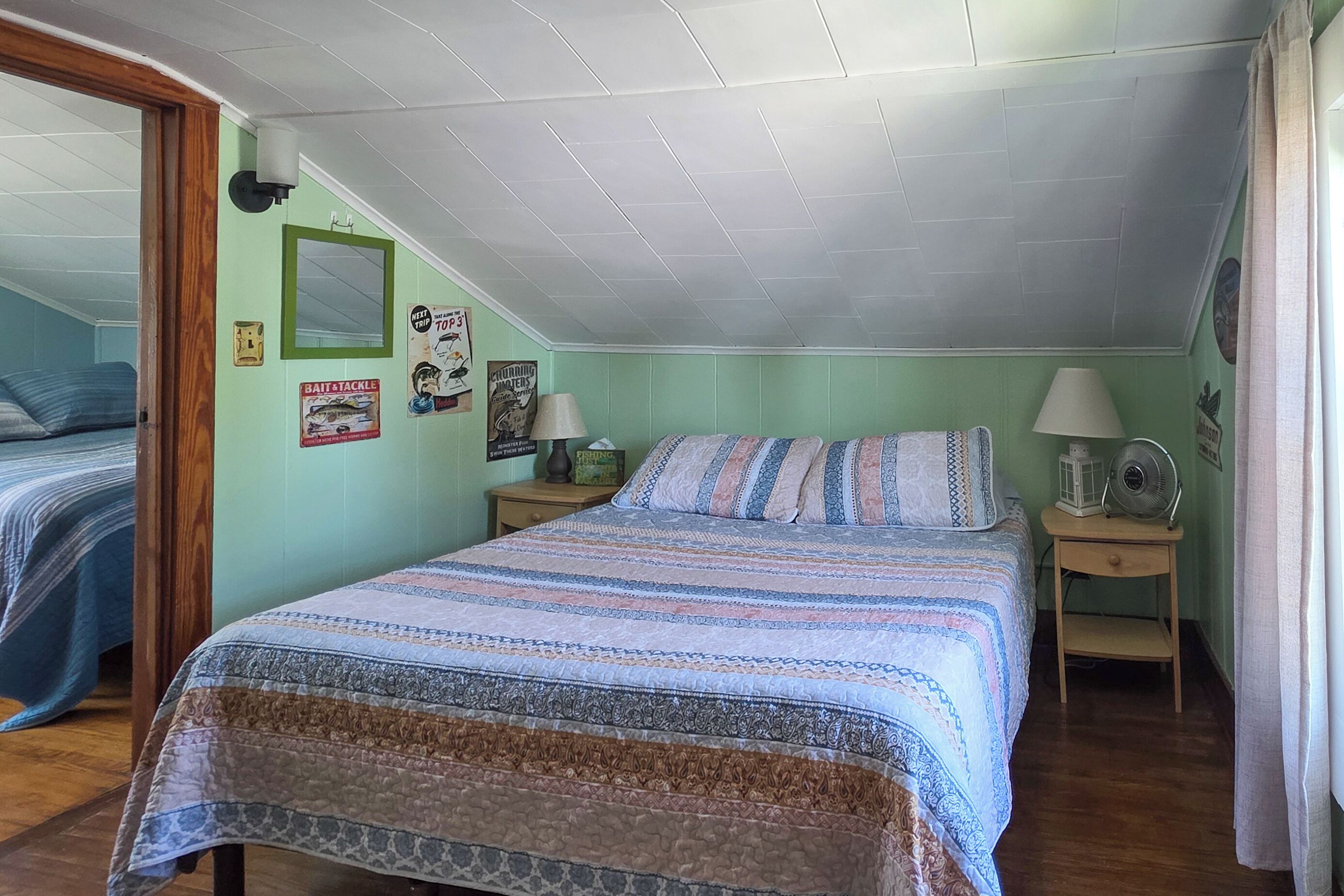 Une chambre à coucher avec un lit, deux tables de chevet, une lampe et une affiche accrochée au mur.