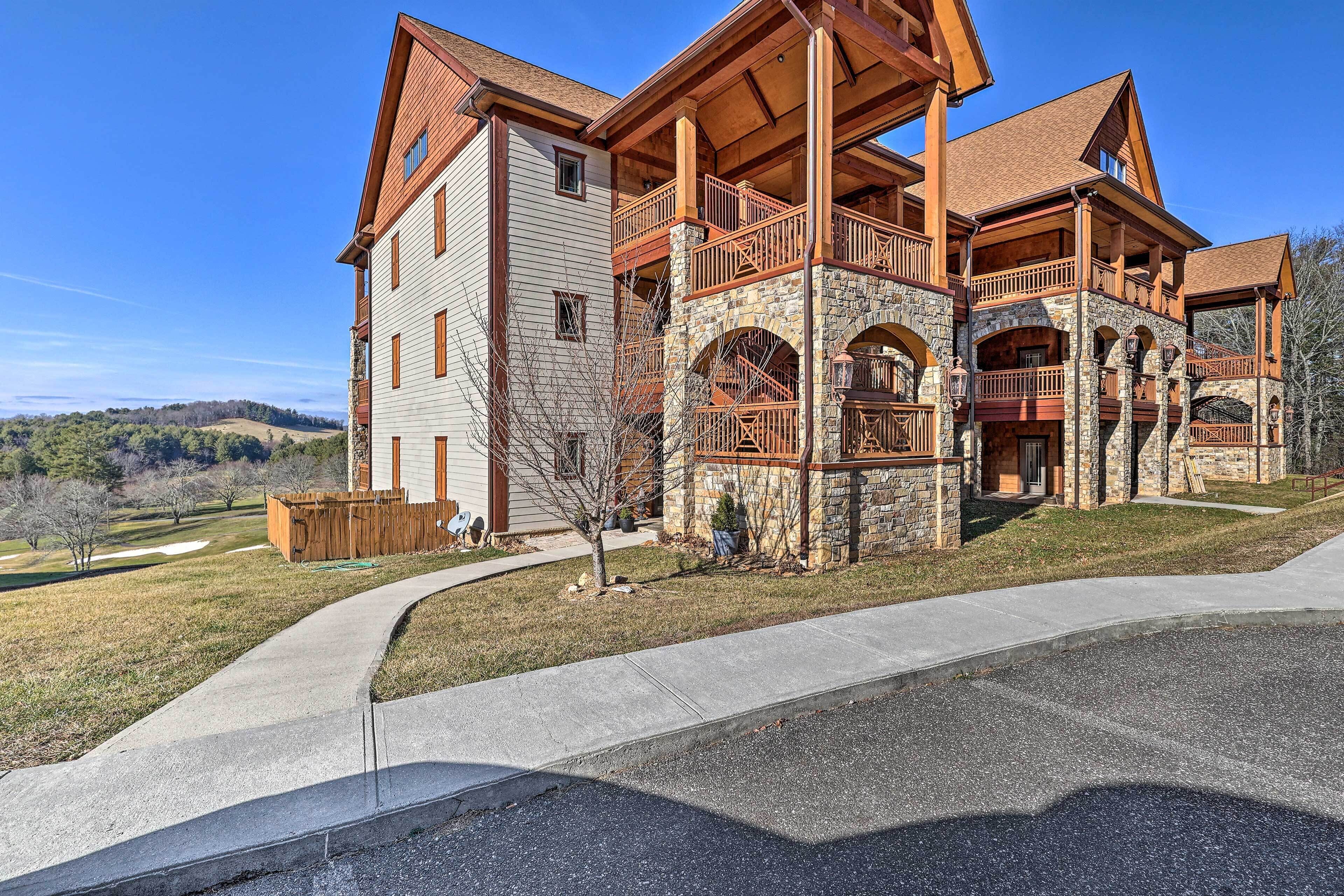 A large, multi-story building with a stone facade, multiple balconies, and a covered outdoor area.