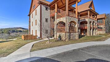 A large, multi-story building with a stone facade, multiple balconies, and a covered outdoor area.
