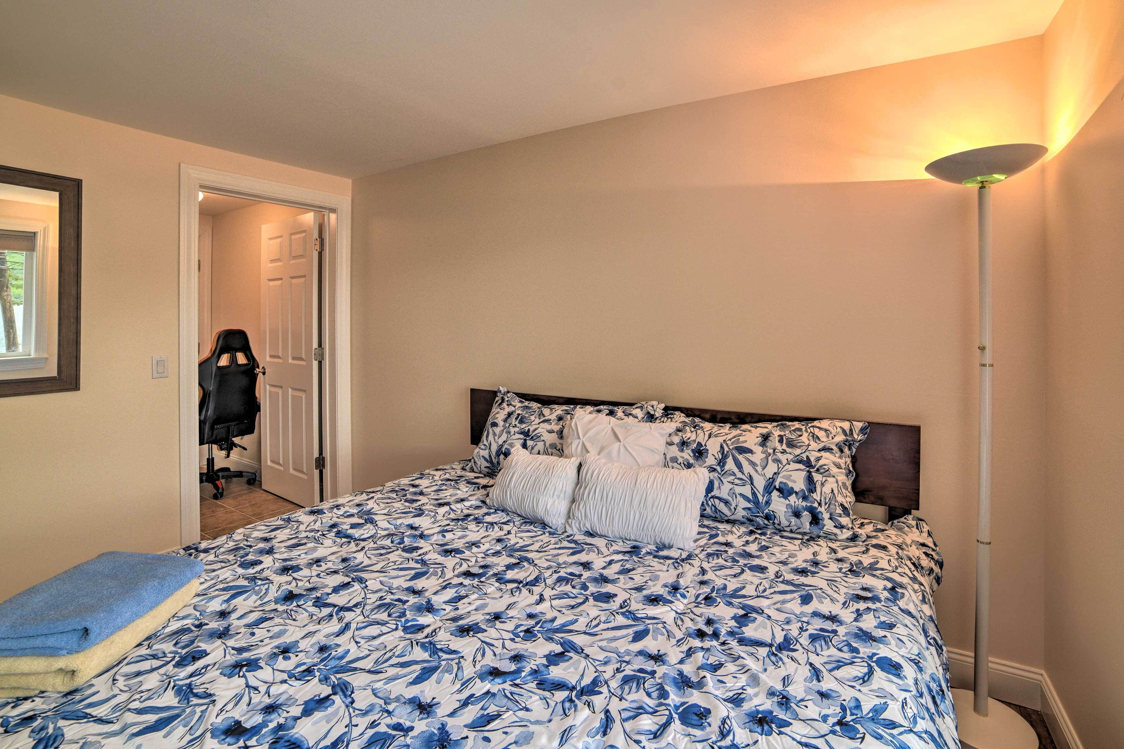 A bedroom with a large bed, a bedside lamp, and a door leading to another room.