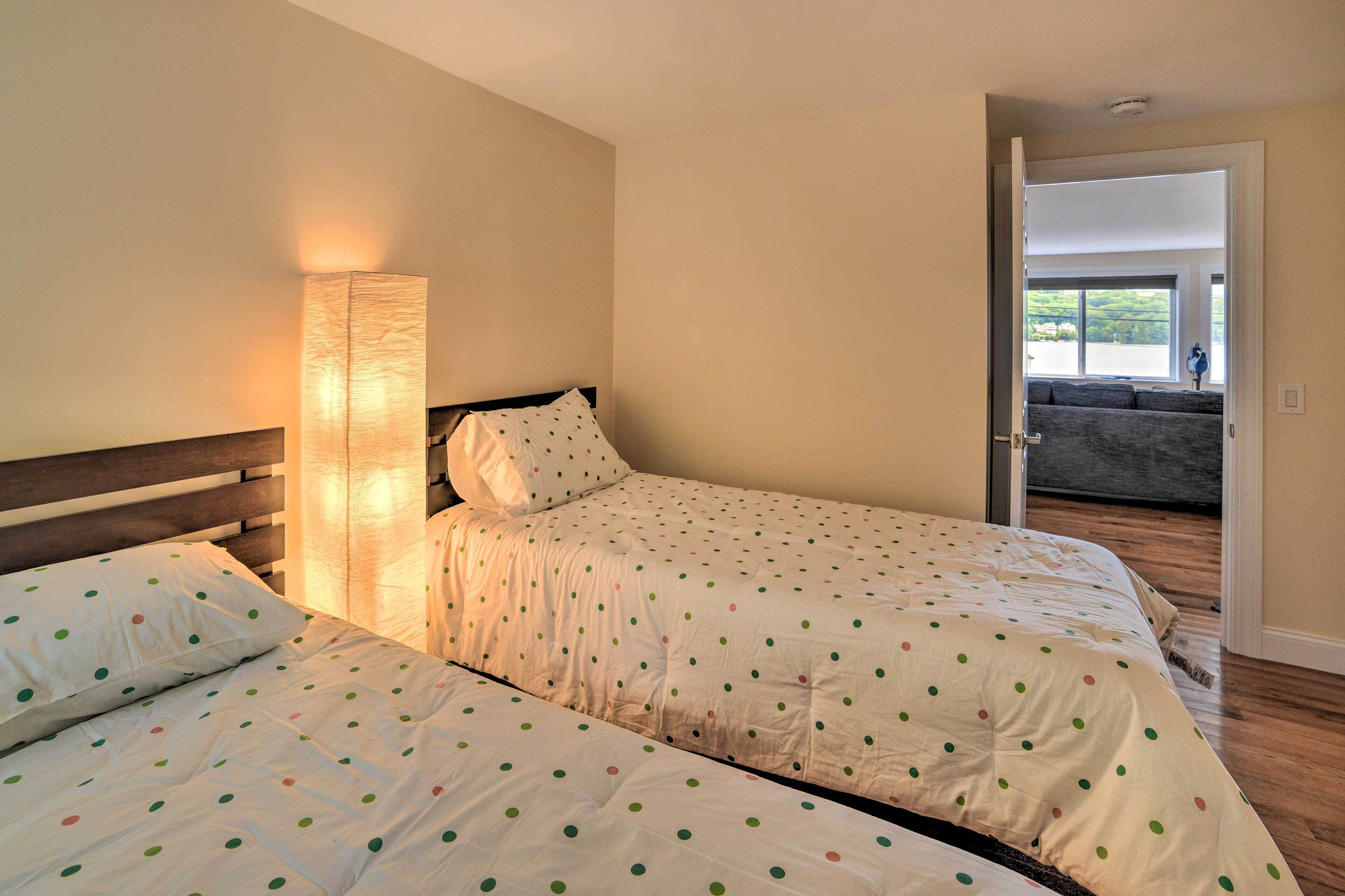 A bedroom with two beds, a nightstand, and a bedside lamp.
