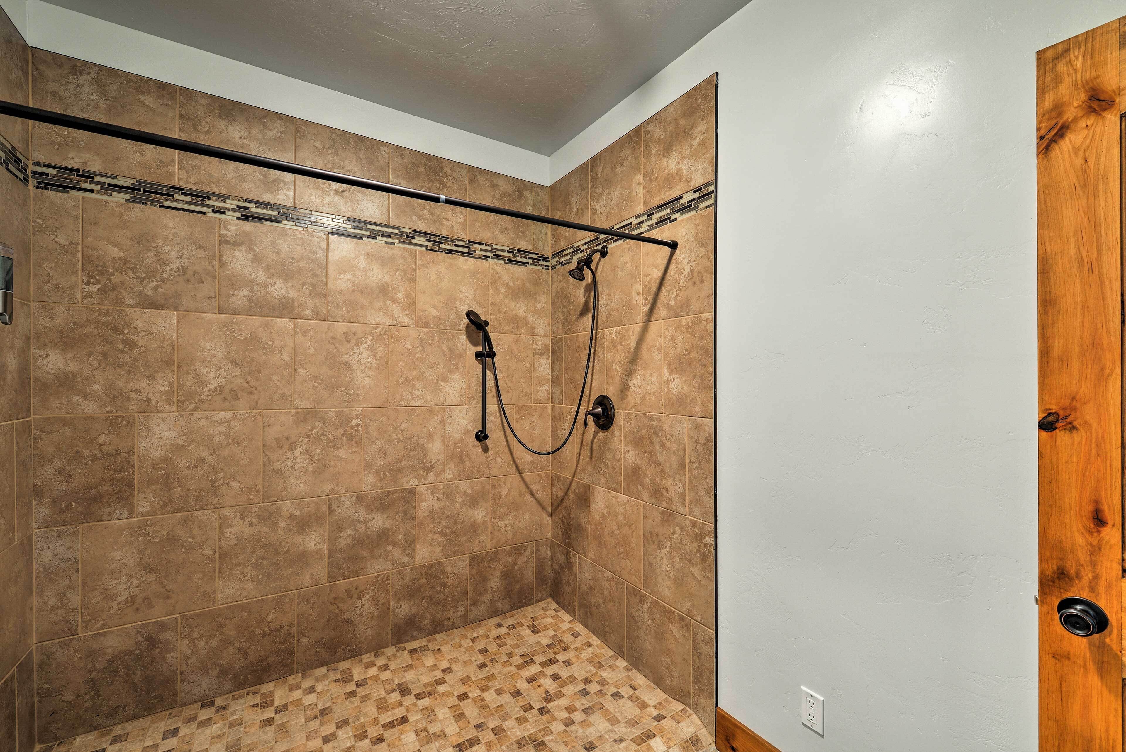 Una ducha con suelo y paredes de azulejos, una puerta de madera y un techo con textura.