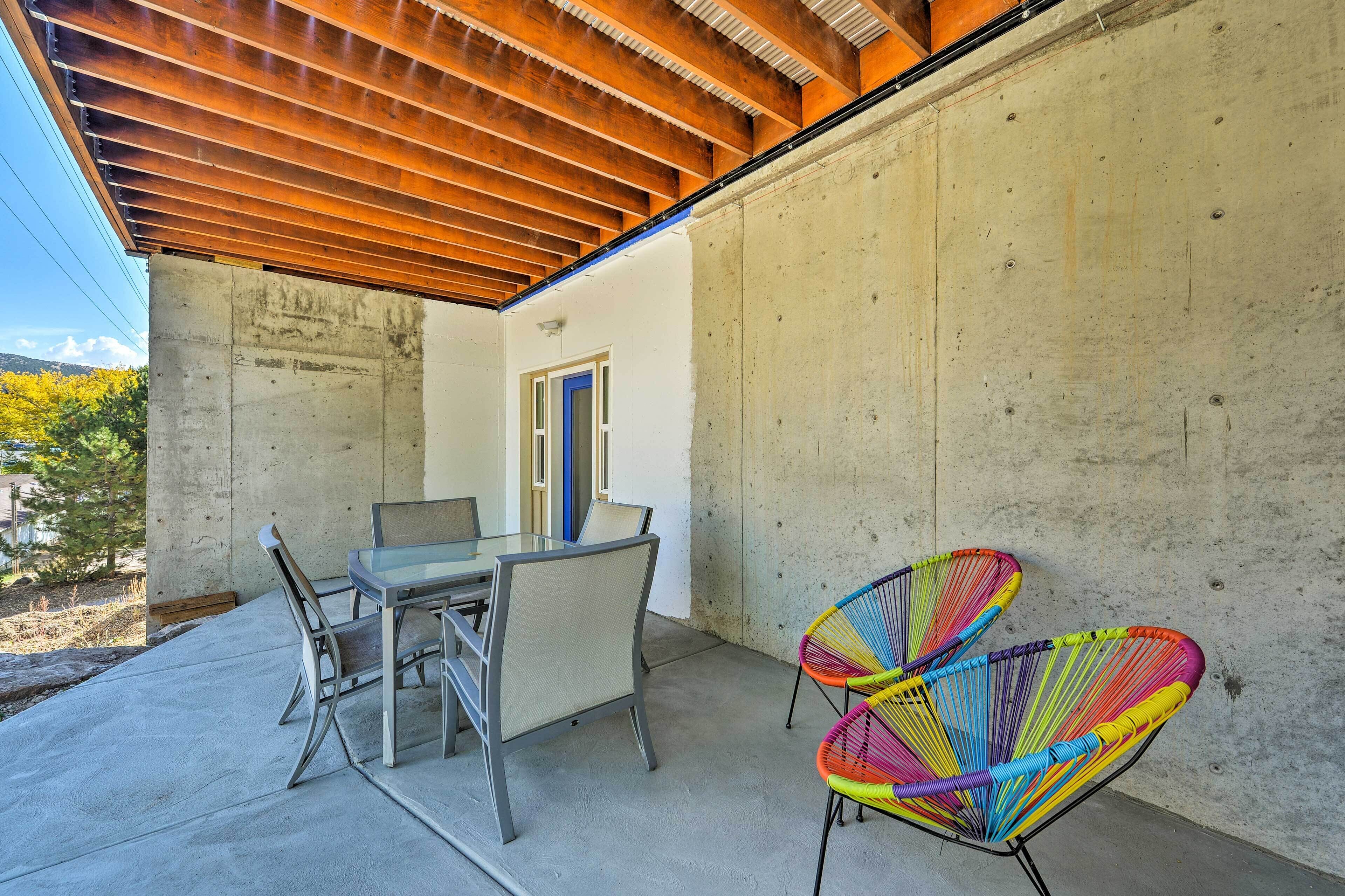 Un patio con una mesa y sillas, un muro de concreto y un techo de madera.