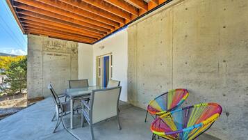 Un patio con una mesa y sillas, un muro de concreto y un techo de madera.