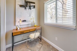 A room with a desk, a chair, a window with blinds, and a painting on the wall. - Spacious Lakefront Home in White Lake (White Lake)