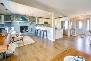 A spacious living area with a fireplace, wooden flooring, and a kitchen with white cabinets and a blue accent wall. - Spacious Lakefront Home in White Lake (White Lake)