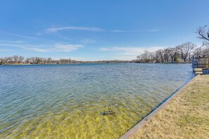 A clear view of a lake with a grassy bank and a wooden dock. - Spacious Lakefront Home in White Lake (White Lake)